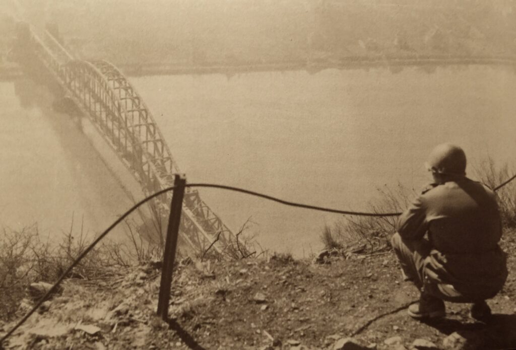 Ein Amerikanischer GI blickt von der Erpeler Ley am Ostufer des Rheins hinunter auf die Eisenbahnbrücke von Remagen. Deutschen Pionieren war die Sprengung nicht gelungen. So fiel den Alliierten dieser Flussübergang in die Hände. Die Deutschen hatten die Sprengung lange hinausgezögert, um den letzten Verbänden der Wehrmacht noch die Flucht über den Fluss zu ermöglichen. Die Amerikaner bildeten so einen ersten Brückenkopf. Am 17. März jedoch brach das beschädigte Bauwerk doch noch zusammen. Foto: US Army