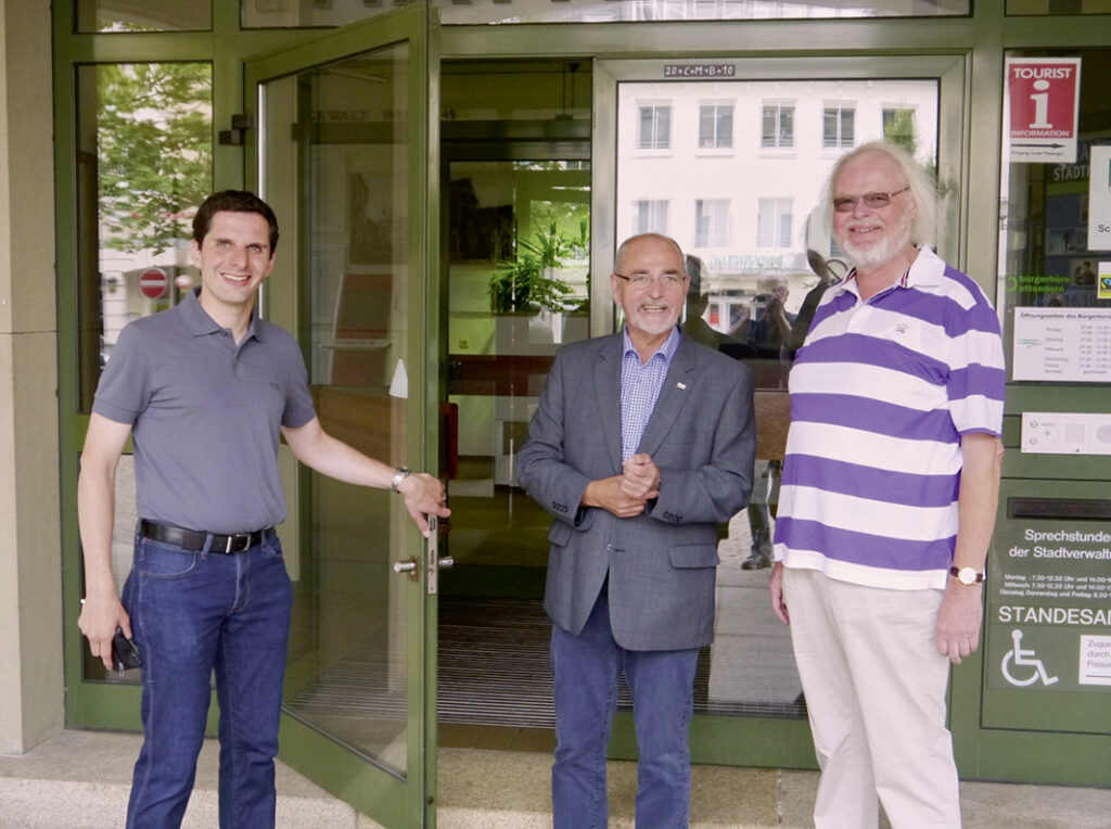 Bürgermeister Christian Pospischil (links) öffnet Regierungspräsident Dr. Gerd Bollermann (Mitte) und seinem Vor-Vorgänger Alfons Stumpf die Tür zum Rathaus.