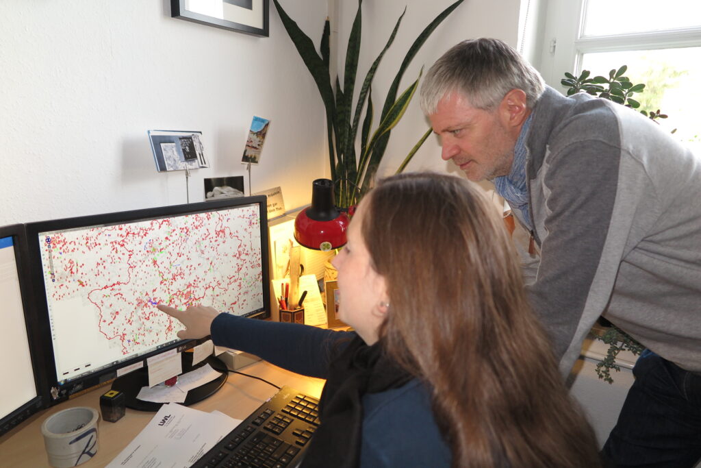 Prof. Dr. Michael Baales schaut zusammen mit seiner Mitarbeiterin, der Archäologin Melanie Röring, auf die dicht bestückte Karte mit der Markierung von archäologischen Fundplätzen im Kreis Olpe. Foto Andrea Arens