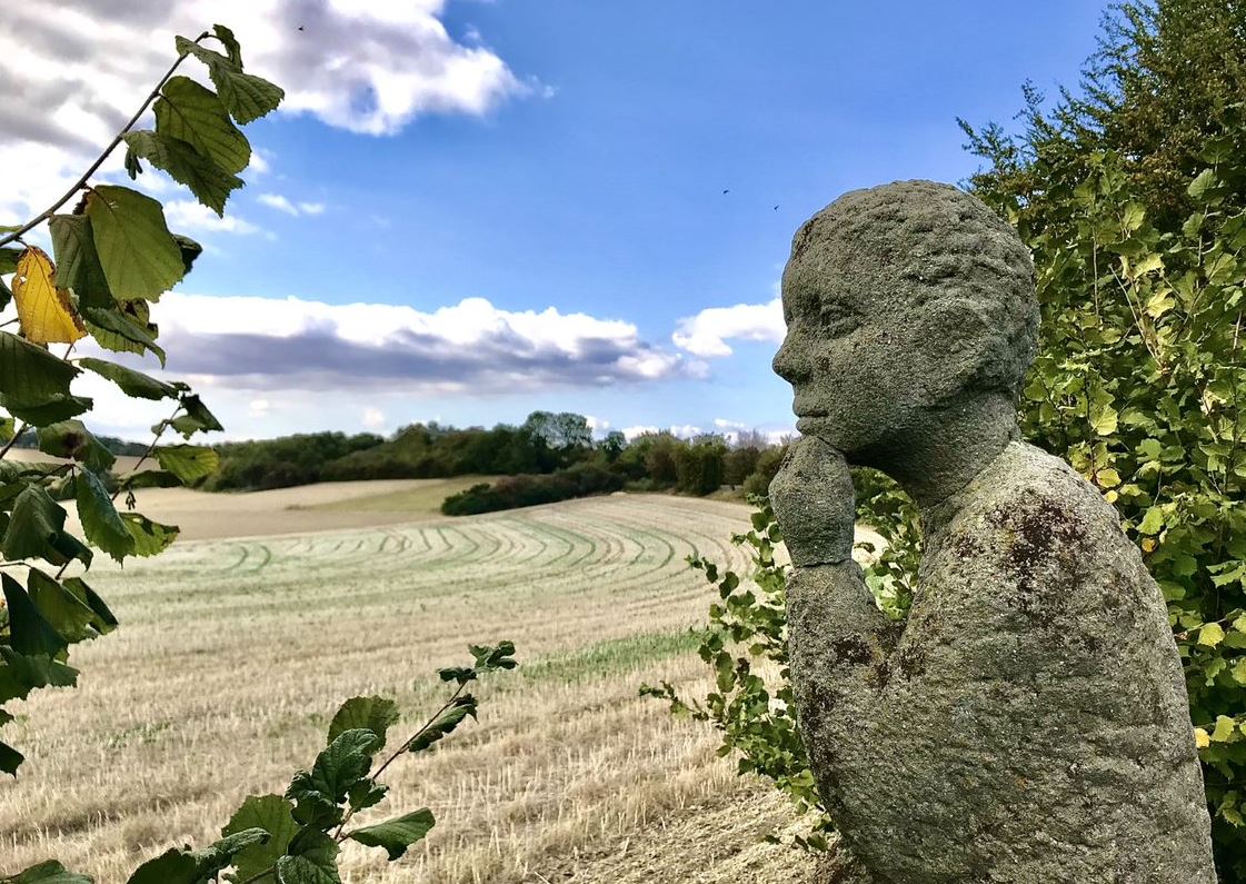 Die nachdenklich anmutende Skulptur aus Grünsandstein blickt über die fruchtbaren Felder der Soester Börde hinunter zum Möhnesee. Foto: Matthias Koprek