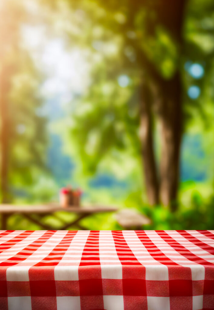 Picnic table with red and white checkered tablecloth on it. Generative AI.